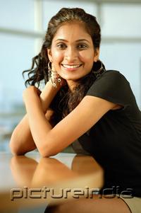 PictureIndia - Woman smiling at camera, hand on head, arms crossed