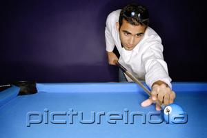 PictureIndia - Young man preparing to hit pool ball