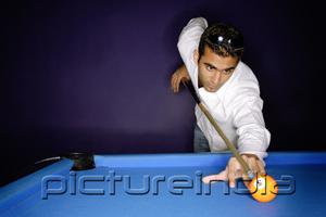 PictureIndia - Young man preparing to hit pool ball