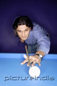 PictureIndia - Man with pool cue preparing to hit ball