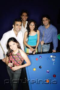 PictureIndia - Young adults standing around pool table