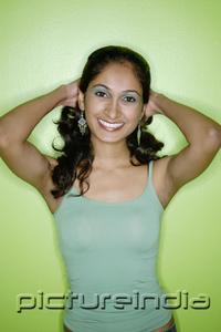 PictureIndia - Young woman in green tank top, against green background