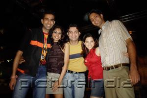 PictureIndia - Young adults standing side by side, smiling at camera