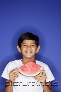 PictureIndia - Boy looking at camera, holding watermelon slice