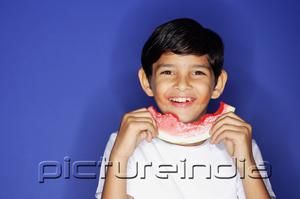 PictureIndia - Boy looking at camera, holding half eaten slice of watermelon