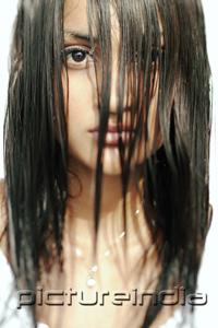 PictureIndia - Young woman looking at camera, long wet hair covering her face