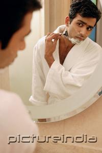 PictureIndia - Man looking in bathroom mirror, shaving his face