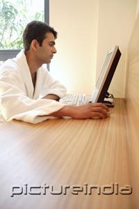 PictureIndia - Man in bathrobe, looking at computer