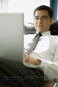 PictureIndia - Businessman reclining on chair with laptop