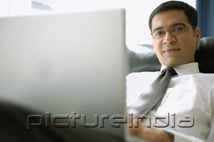 PictureIndia - Businessman with laptop, looking at camera, portrait