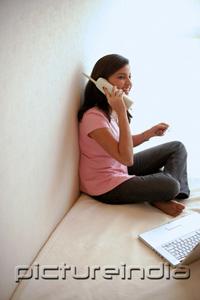 PictureIndia - Woman at home, holding credit card, talking on cordless phone