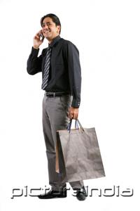 PictureIndia - Businessman carrying shopping bags, talking on mobile phone