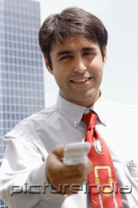 PictureIndia - Businessman holding mobile phone towards camera, smiling
