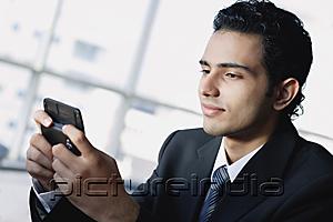 PictureIndia - Young businessman using mobile phone, text messaging