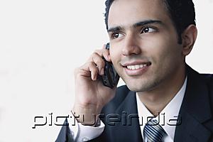 PictureIndia - Young businessman using mobile phone, smiling