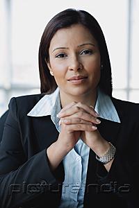 PictureIndia - Businesswoman looking at camera, hands clasped, portrait