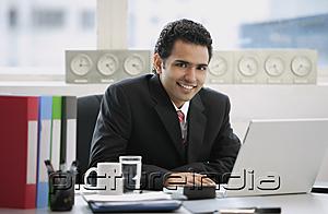 PictureIndia - Businessman sitting in office, smiling at camera
