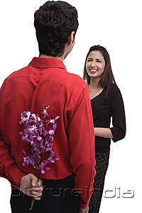 PictureIndia - Man holding flowers behind his back, facing woman