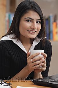 PictureIndia - Woman holding a cup, smiling at camera