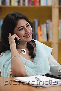 PictureIndia - Woman in library, using mobile phone