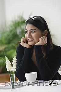 PictureIndia - Woman in cafe, hands on chin, looking away